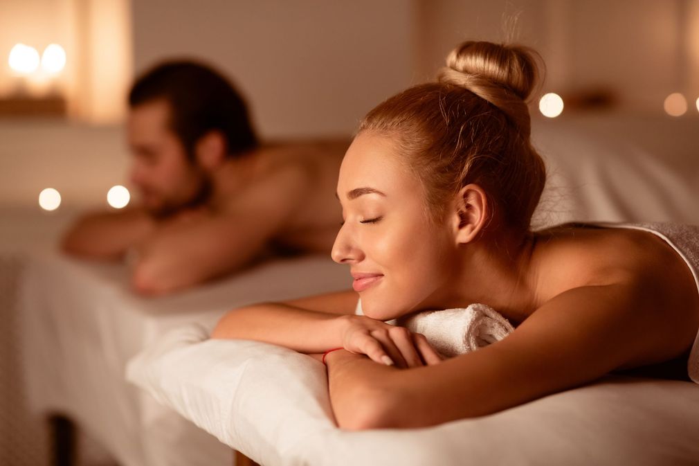 a man and a woman are laying on massage tables in a spa