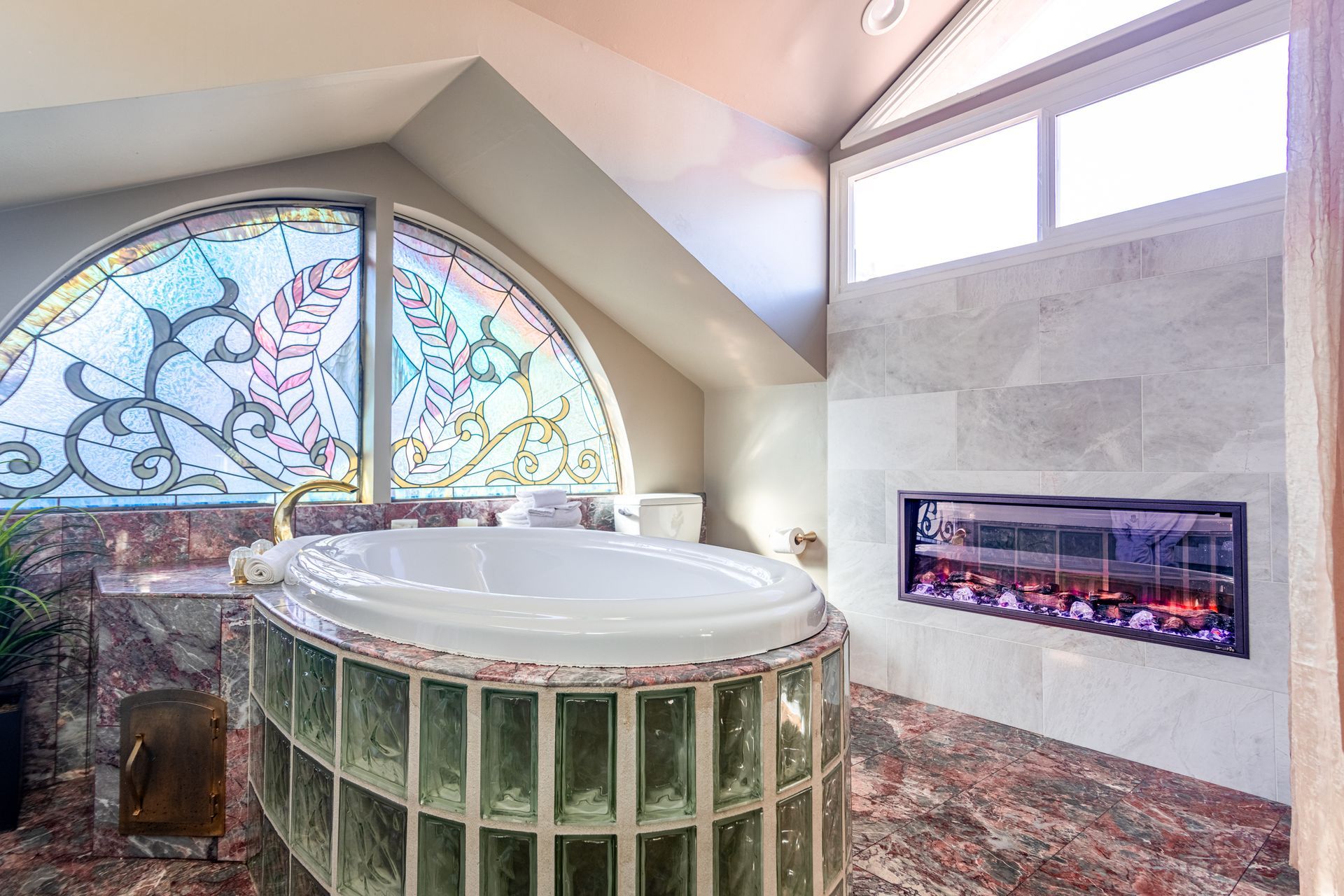 A bathroom with a tub , fireplace and stained glass window.