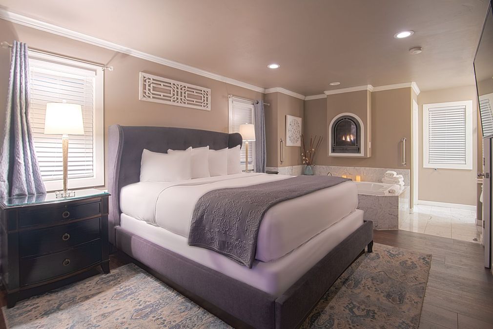 A hotel room with a king size bed and a jacuzzi tub.