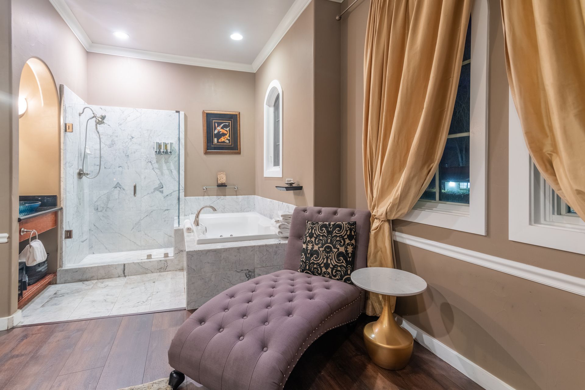 A bathroom with a purple chaise lounge and a jacuzzi tub.