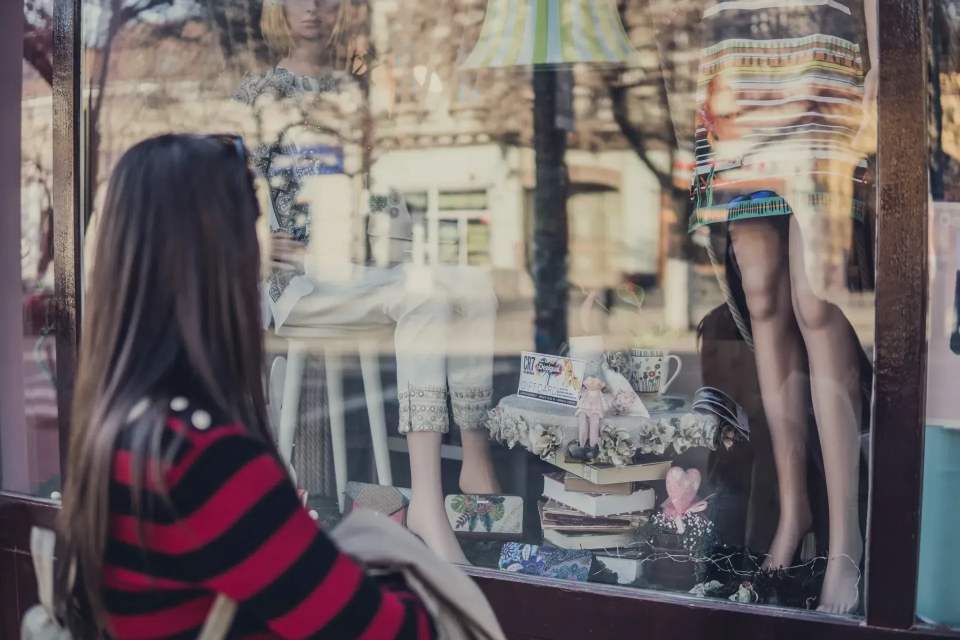 a woman is looking at a mannequin in a store window.