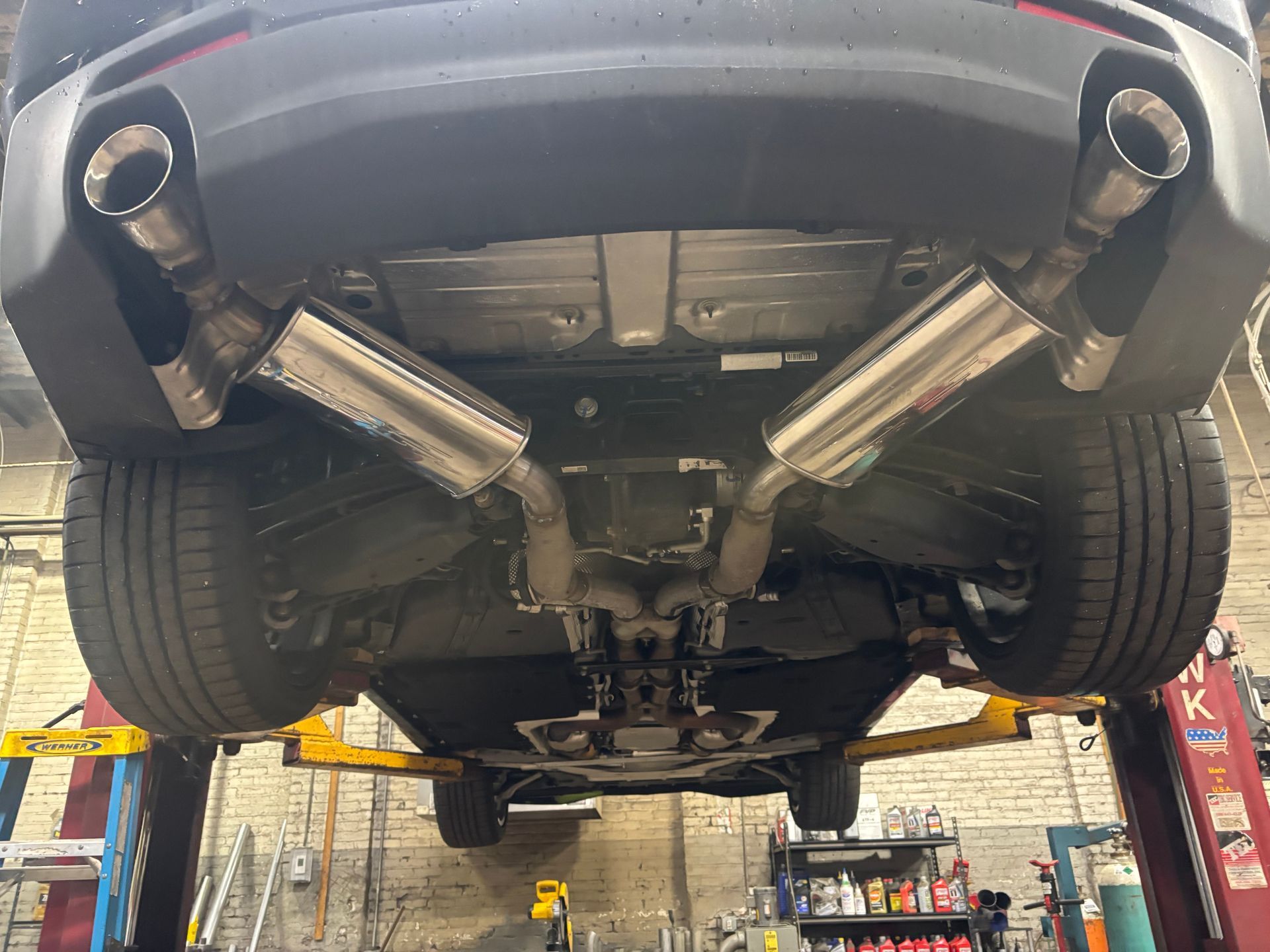 Car exhaust repair and installation at Lou’s Custom Exhaust in Worcester, MA – undercar view of vehicle on lift