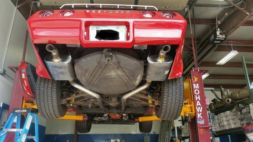 Installing Muffler System On A Red Car — Marlborough, MA — Lou’s Custom Exhaust Of Worcester/Marlborough