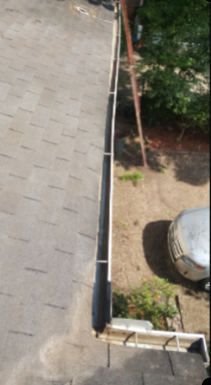 Rooftop with shingles and gutter; a ladder leans against the roof.