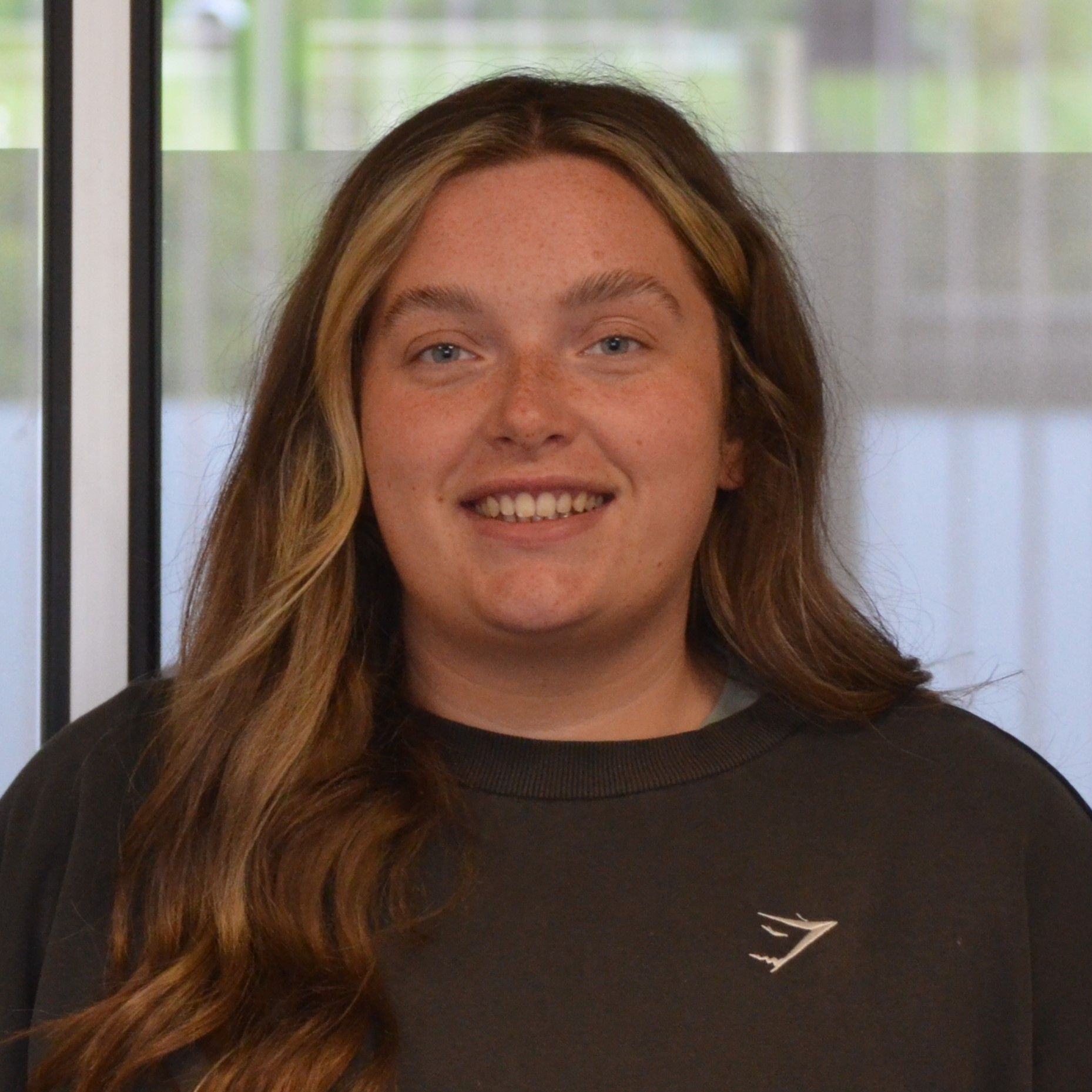 A woman wearing a black sweatshirt is smiling for the camera.