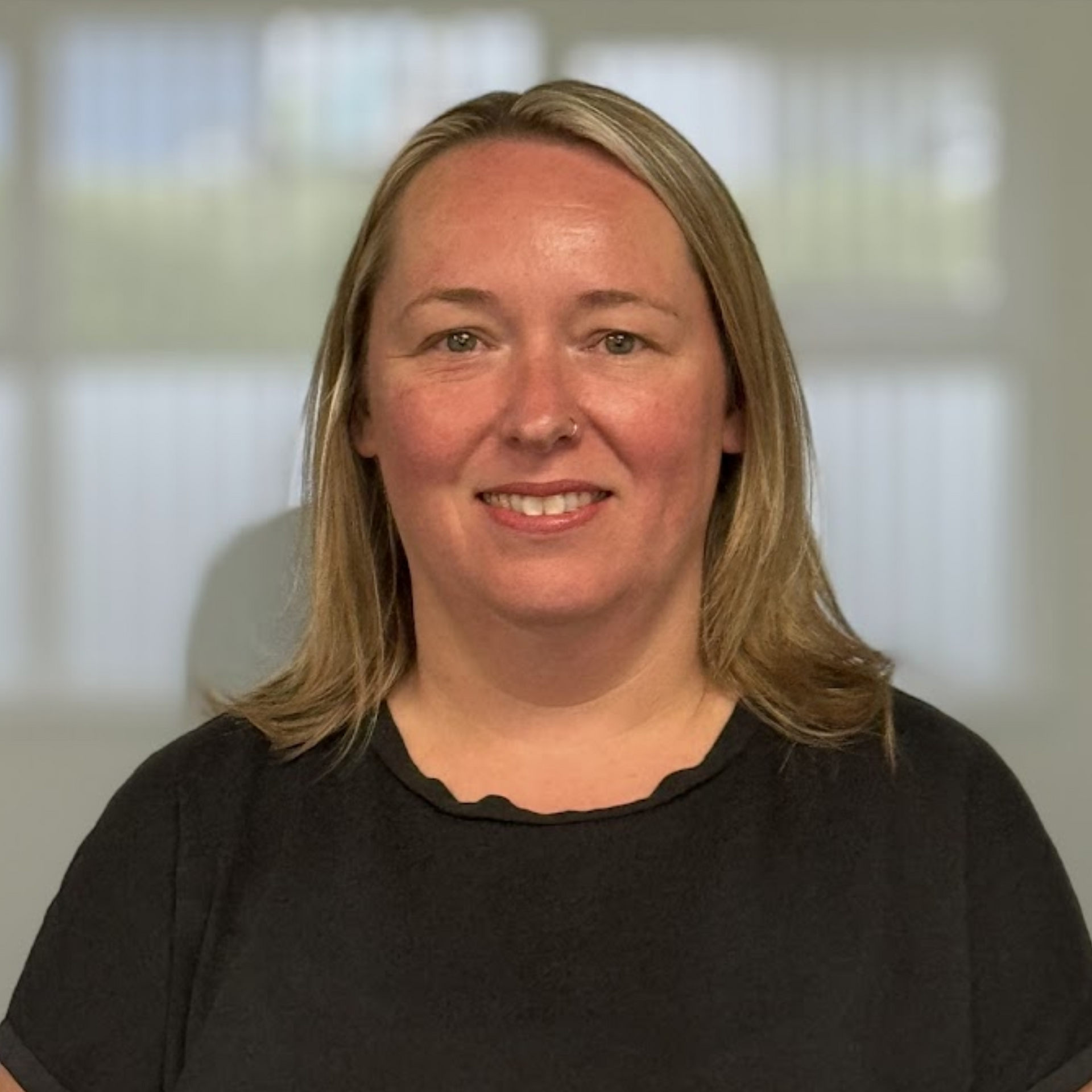 A woman in a black shirt is smiling for the camera.