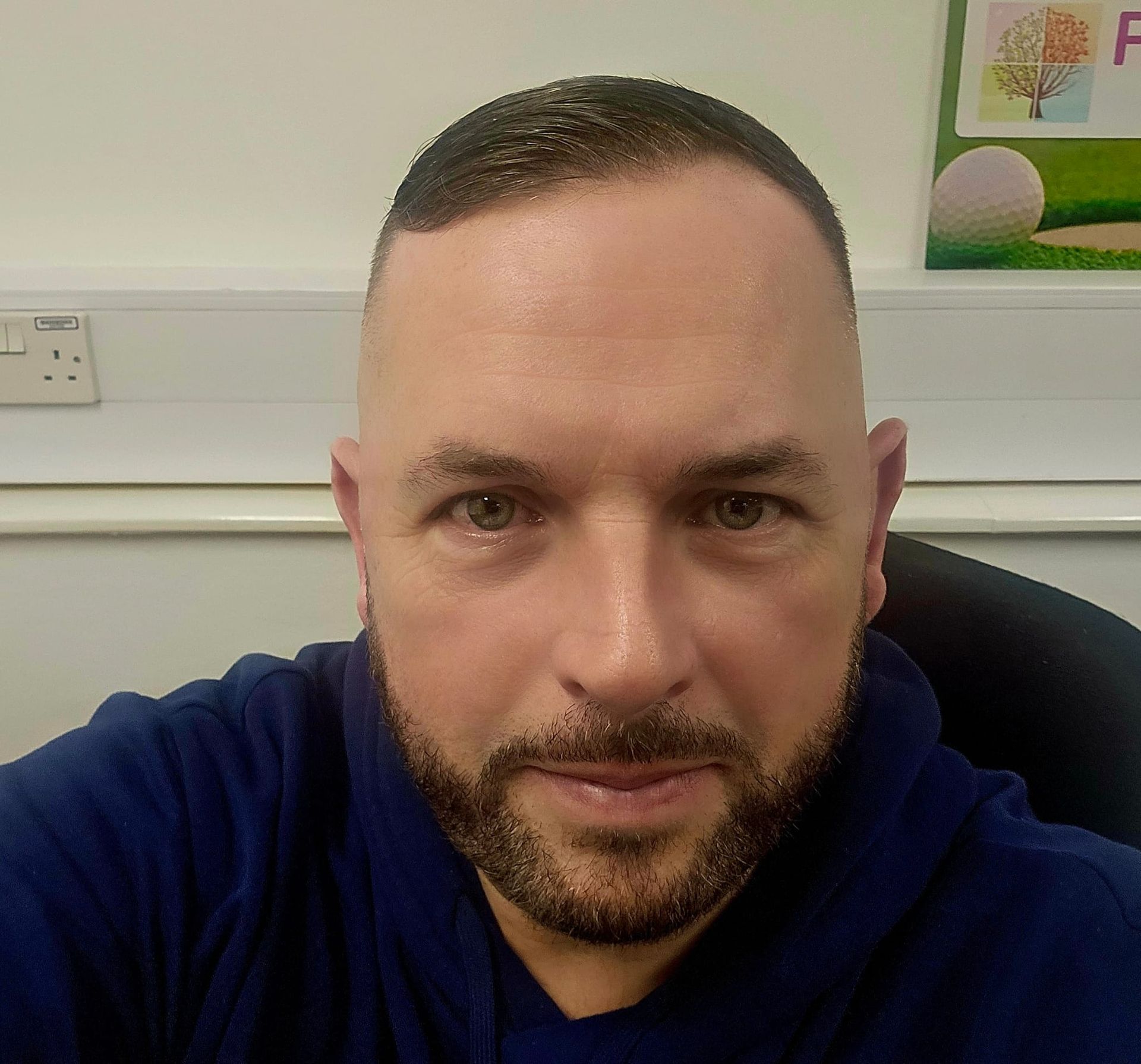 A man in a blue and white checkered shirt is smiling for the camera.