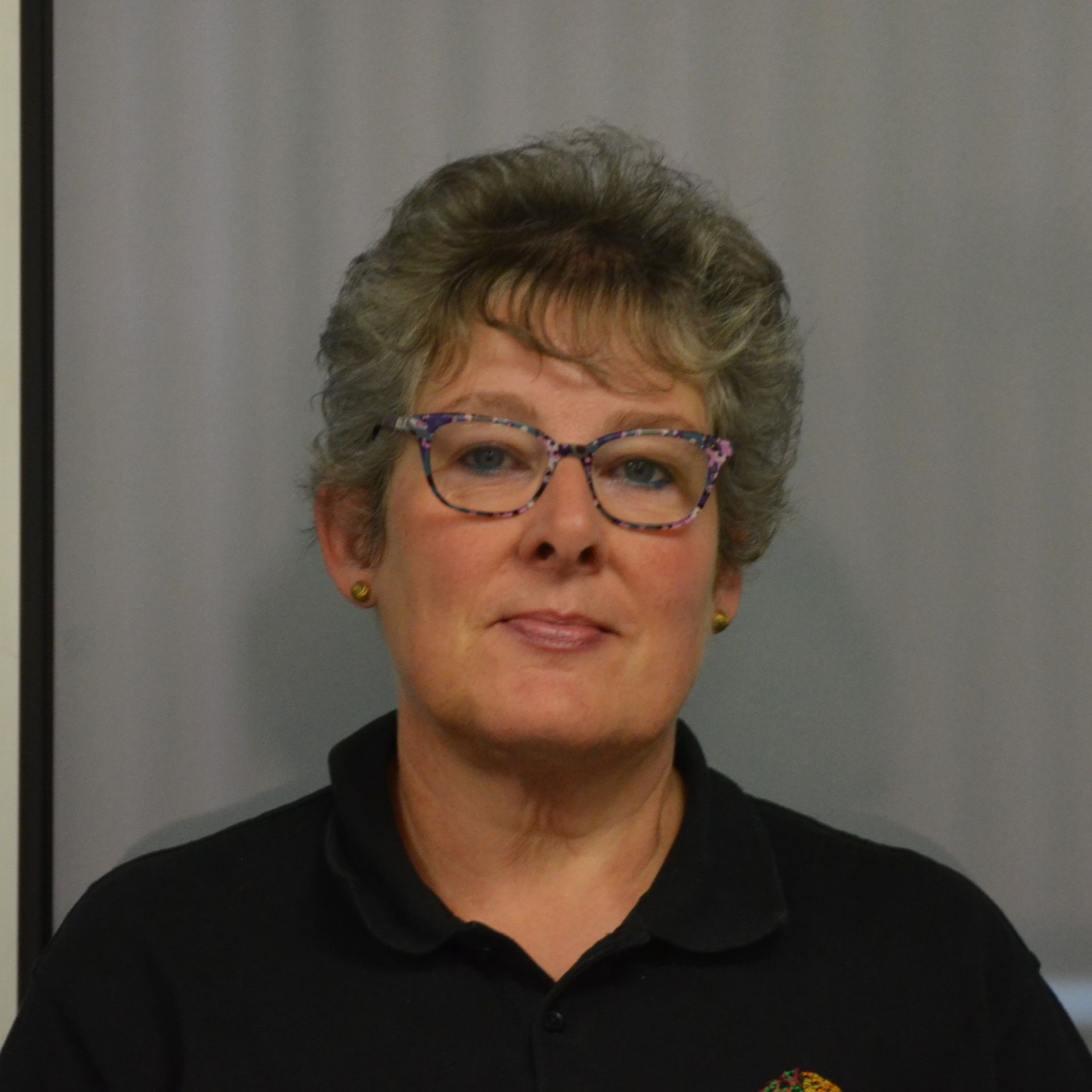 A woman wearing glasses and a black shirt is smiling for the camera.