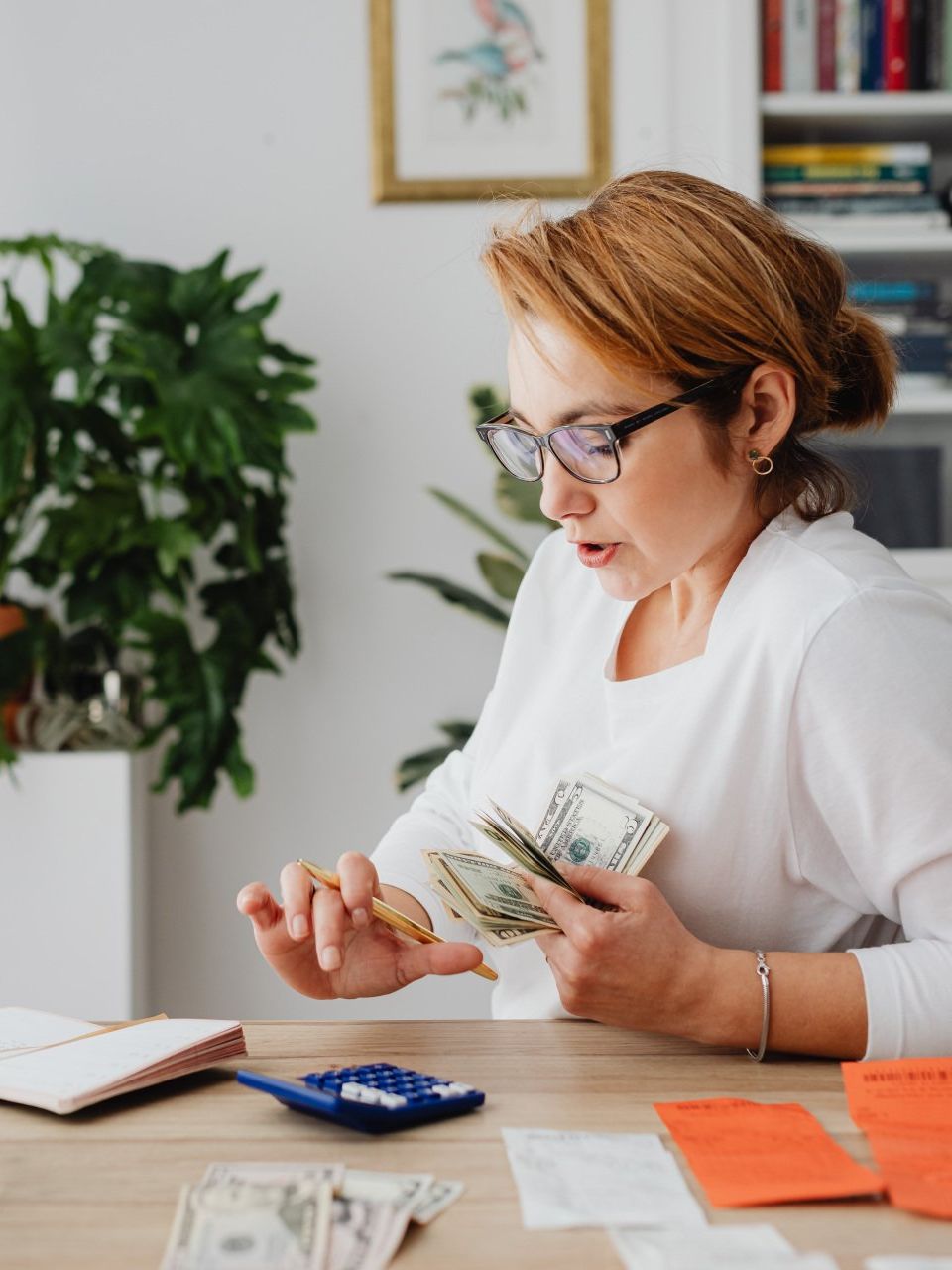 A woman sits down and is counting money. She is holding money in her left hand.