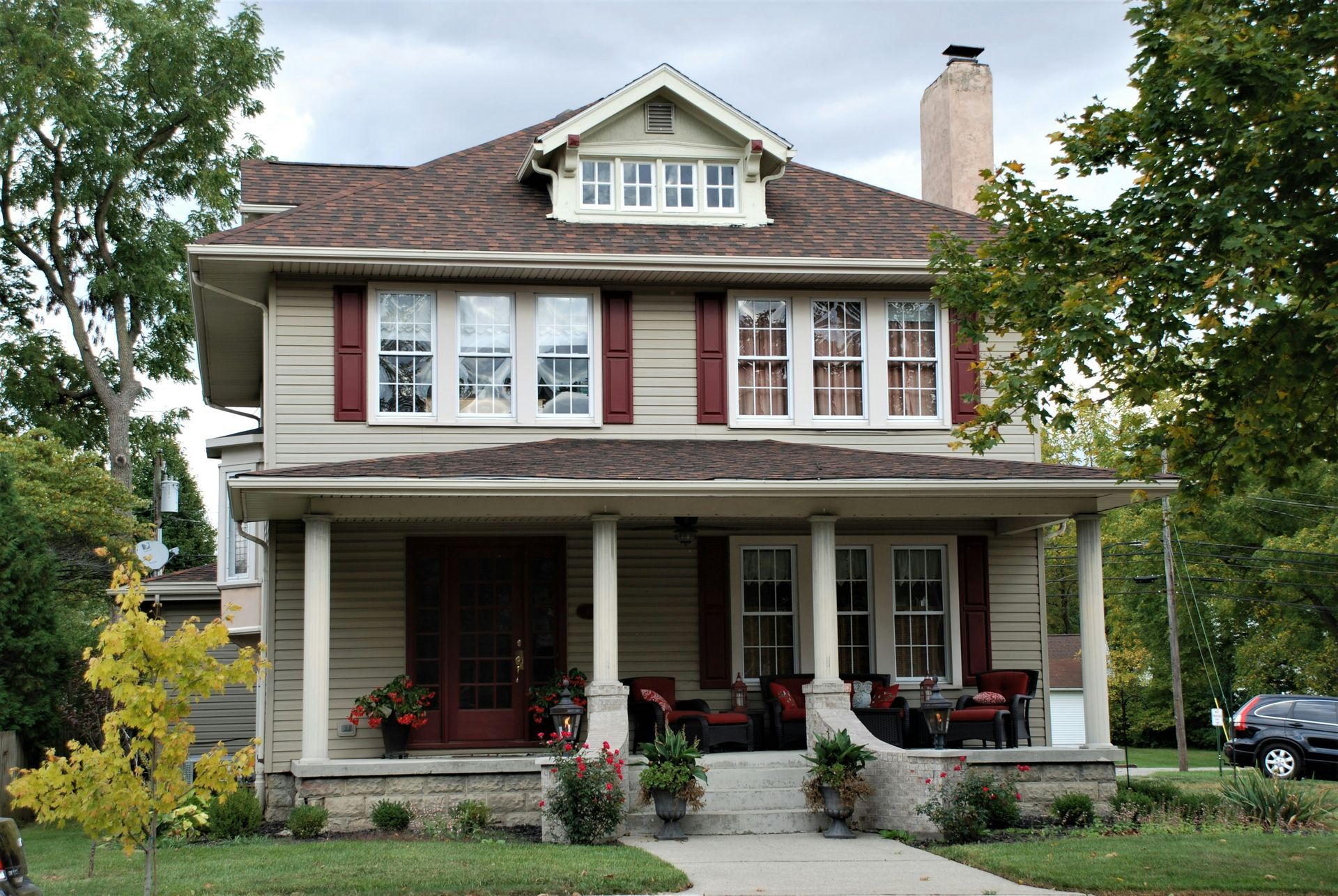 A large house with a porch and a car parked in front of it