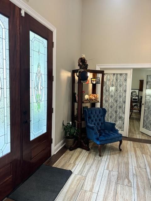 Entryway with wood doors, stained glass, blue velvet chair, and shelving unit with decor.