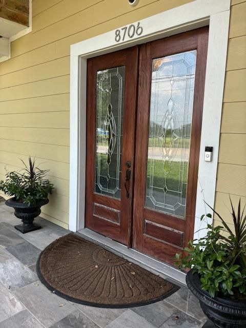 Double wooden front doors with glass panels, address number 