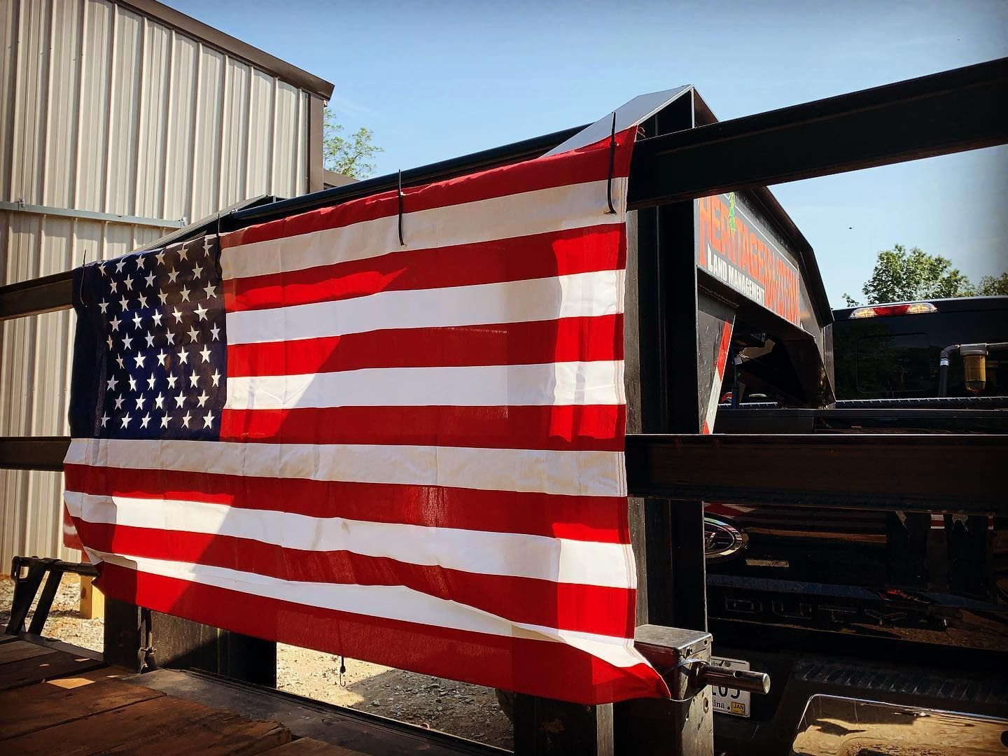 American flag draped over a black metal trailer frame outdoors.