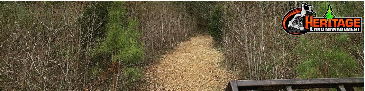 Trail through forest with a Heritage logo in the top right corner.