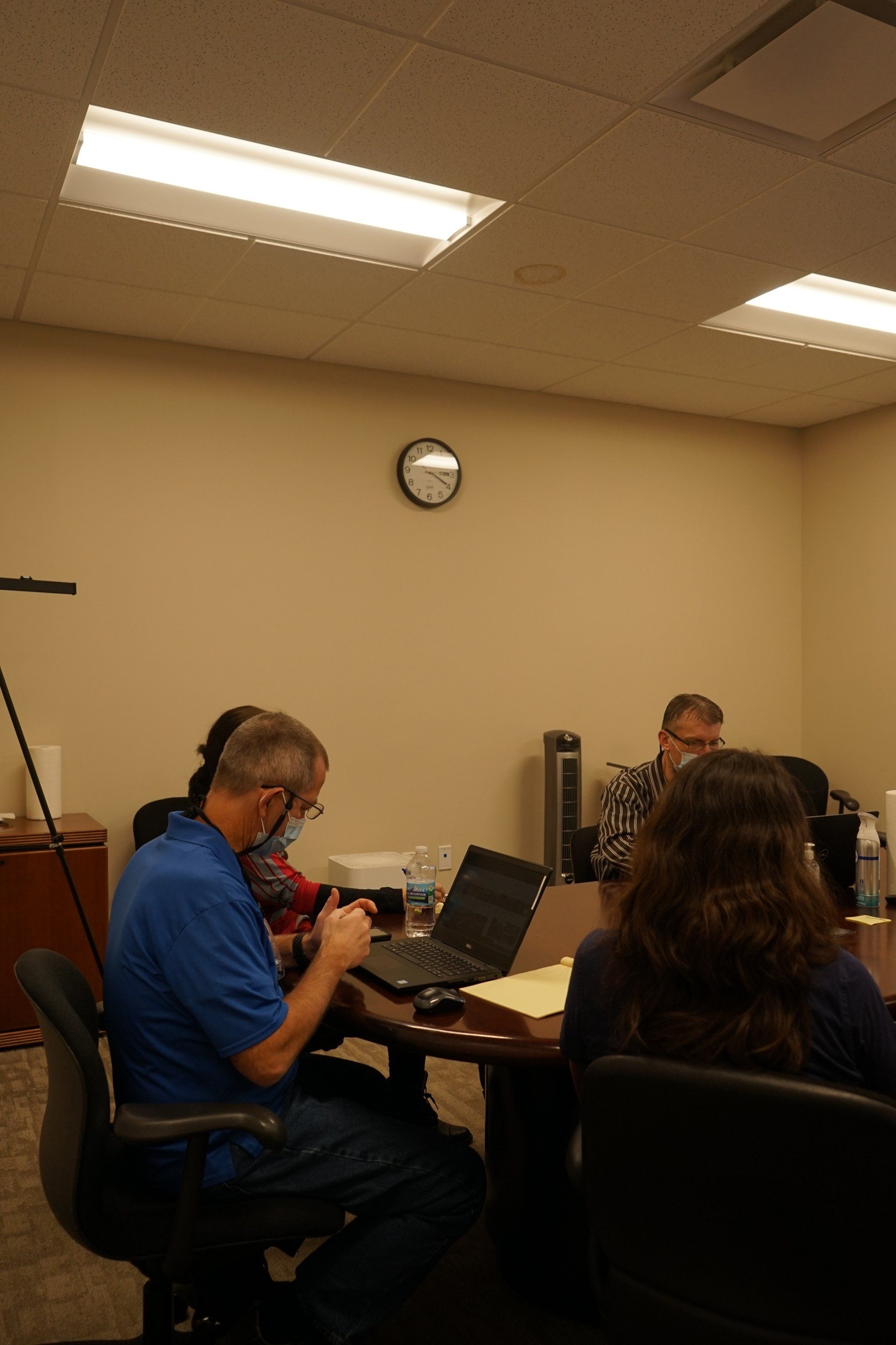 A group of people are sitting around a table with laptops