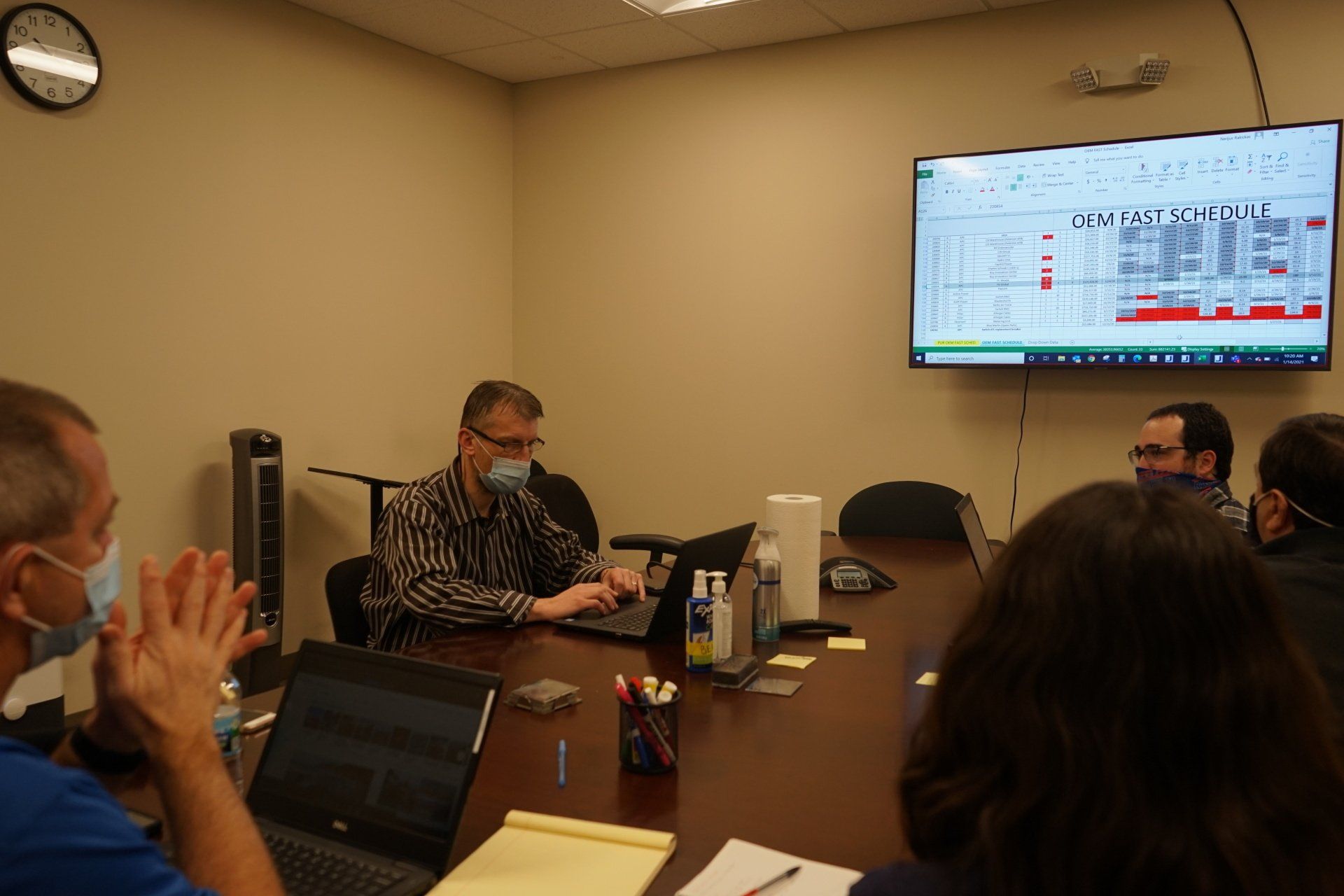 A group of people are sitting around a conference table with laptops.