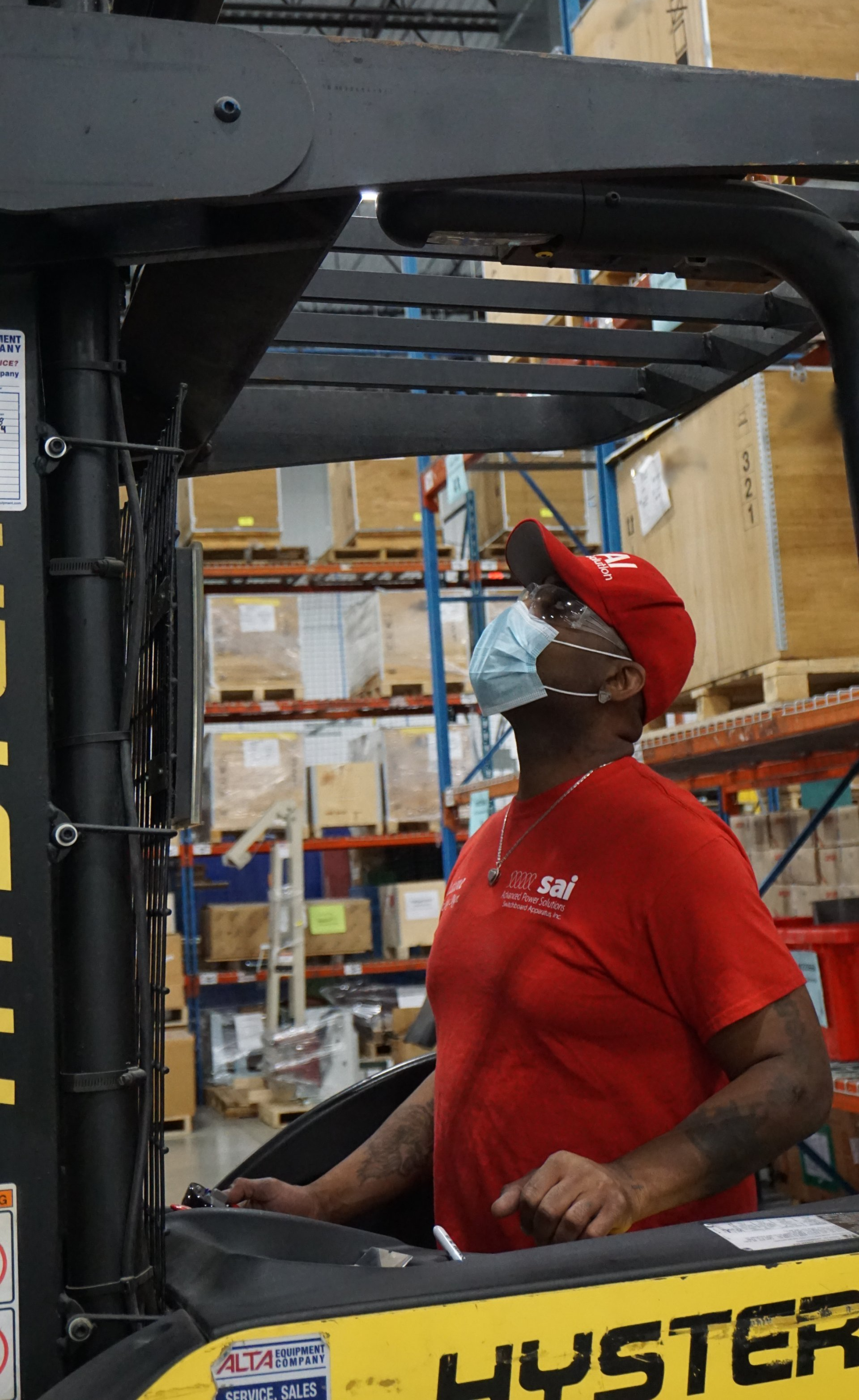 A man wearing a mask is driving a forklift in a warehouse.