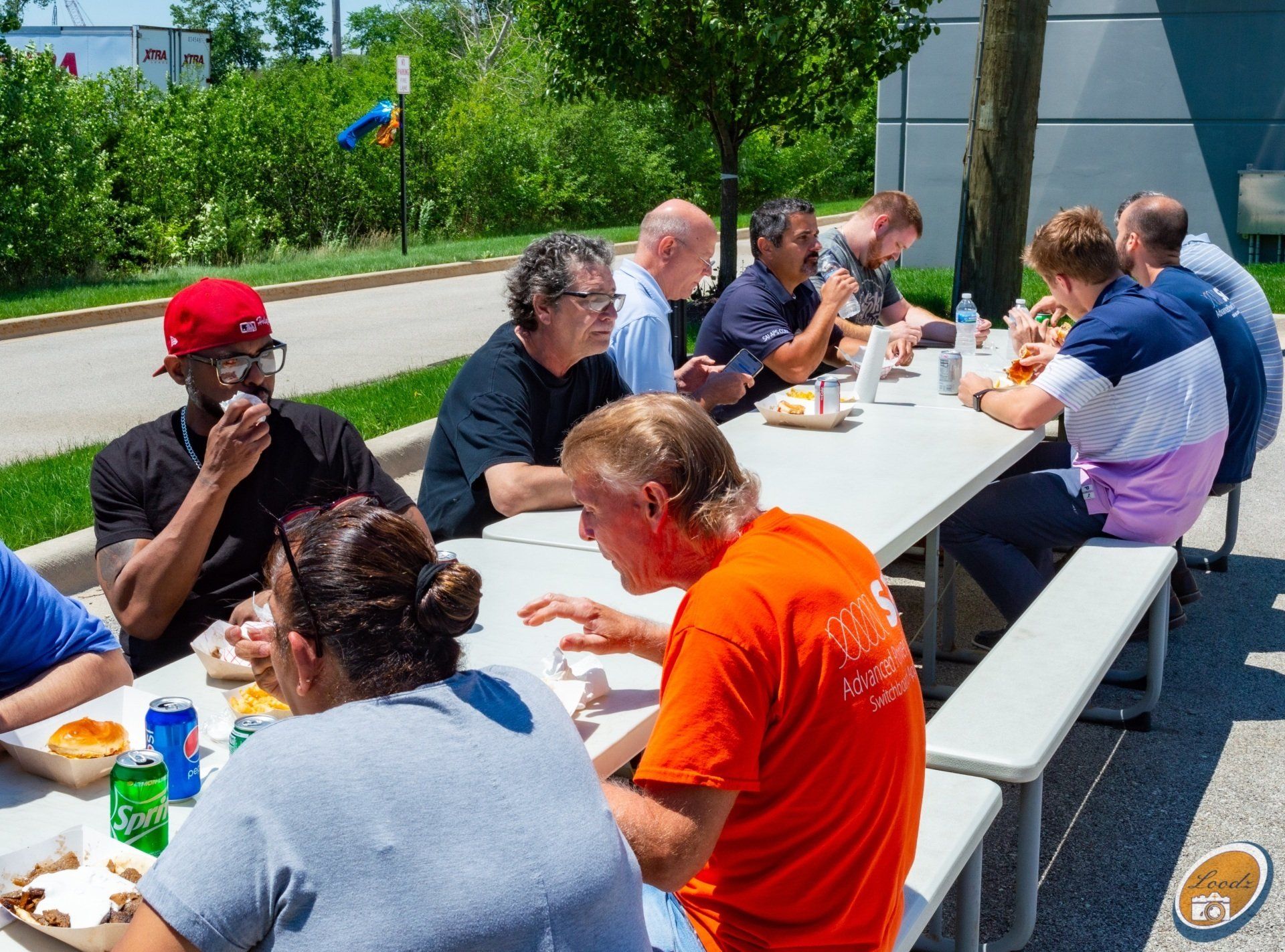 A group of people are sitting at a picnic table eating food.