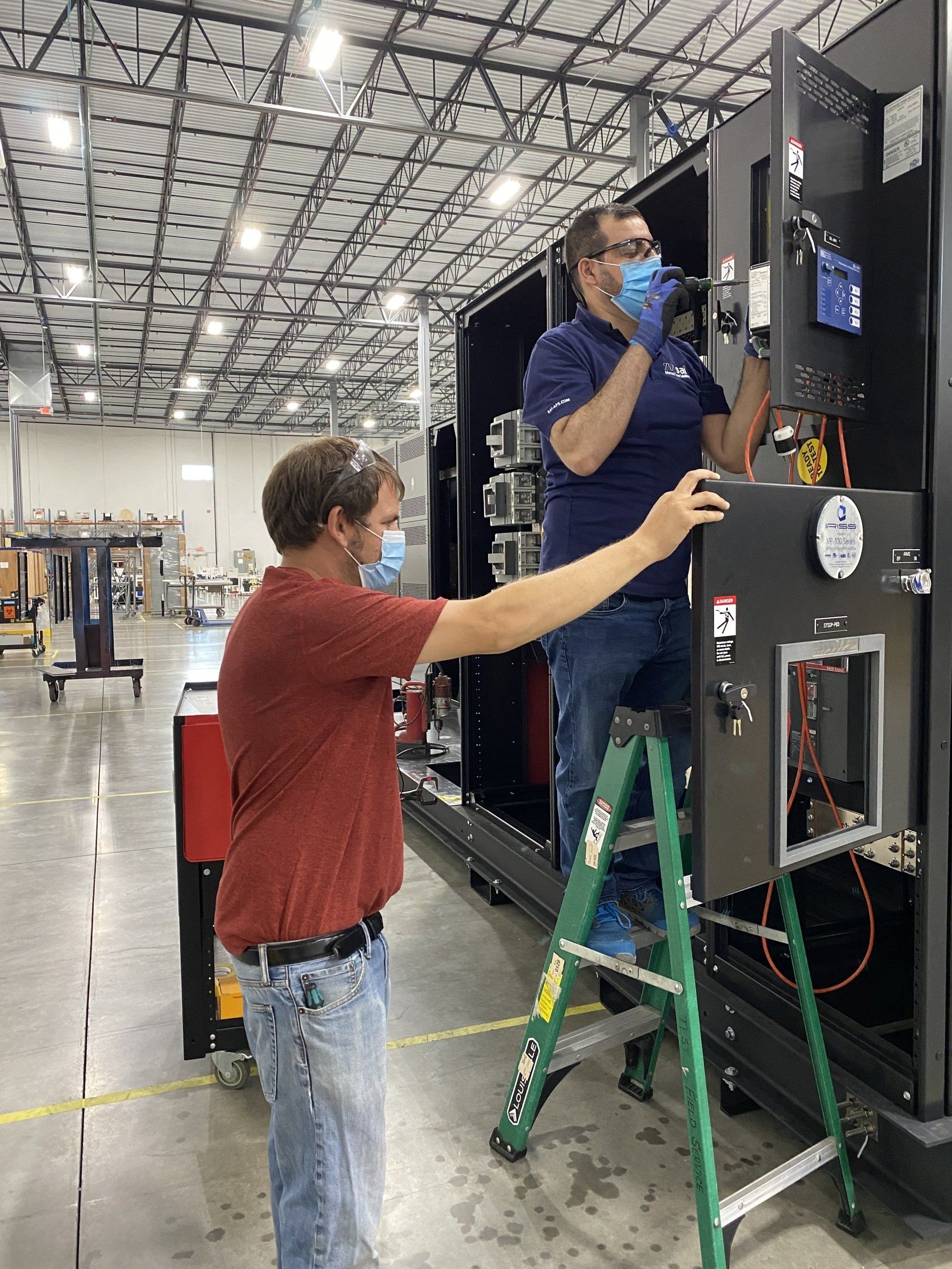 Two men are working on a machine in a warehouse.