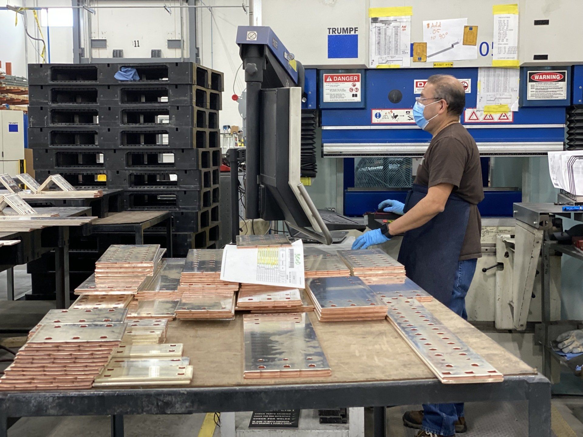 A man in an apron is working on a machine in a factory