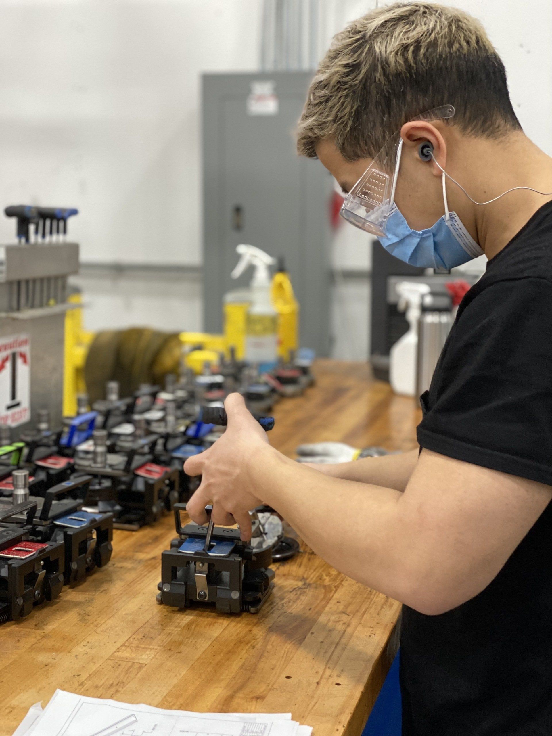 A man wearing a mask is working on a machine