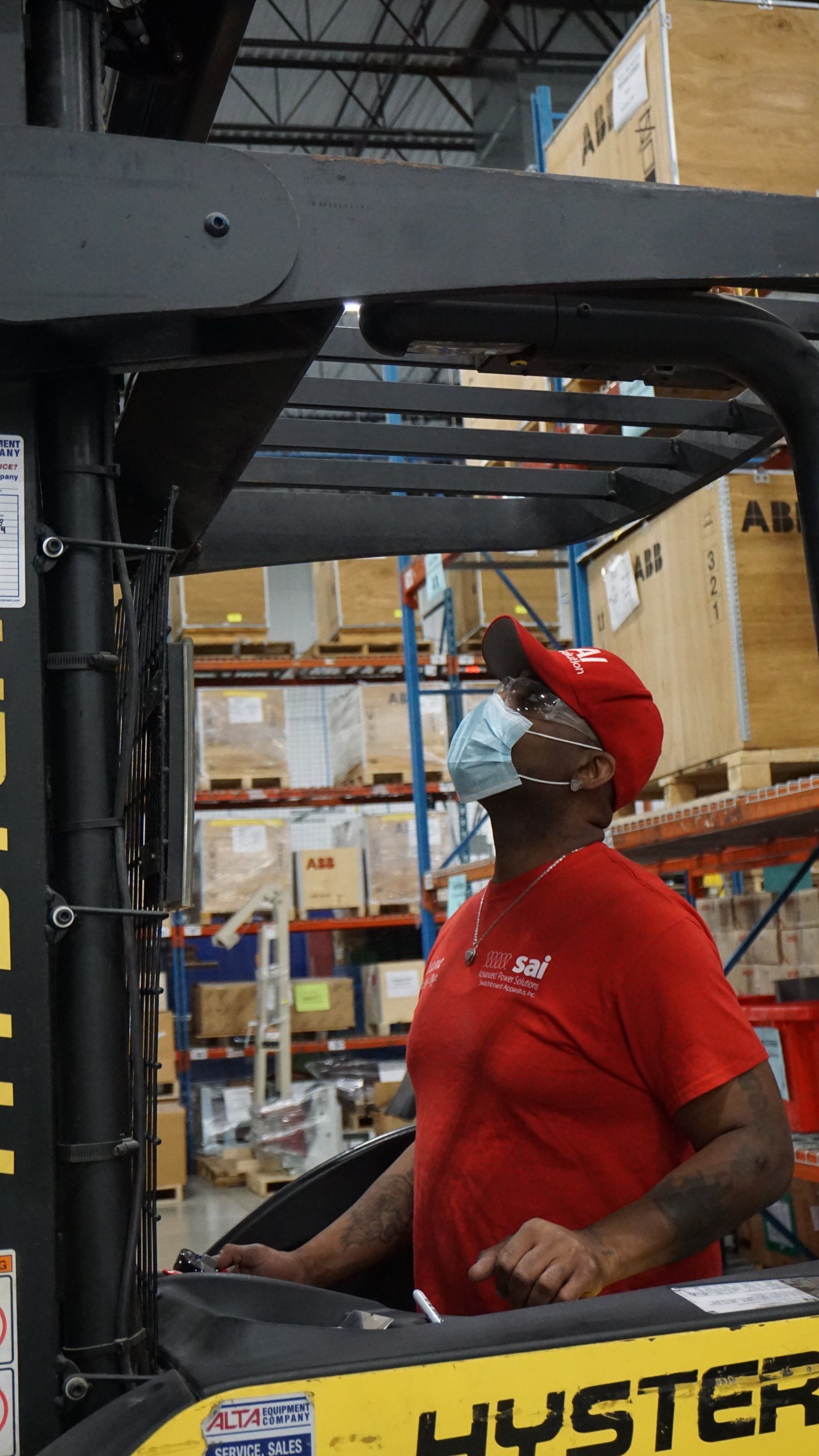 A man wearing a mask is driving a forklift in a warehouse.