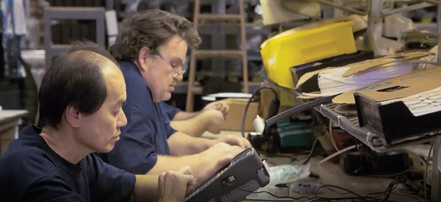 Two men are working on a computer in a factory.