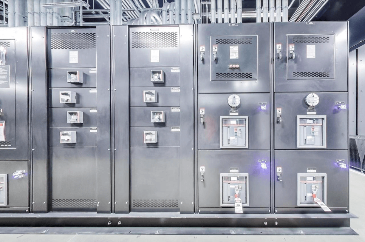 A row of stainless steel electrical cabinets in a building.