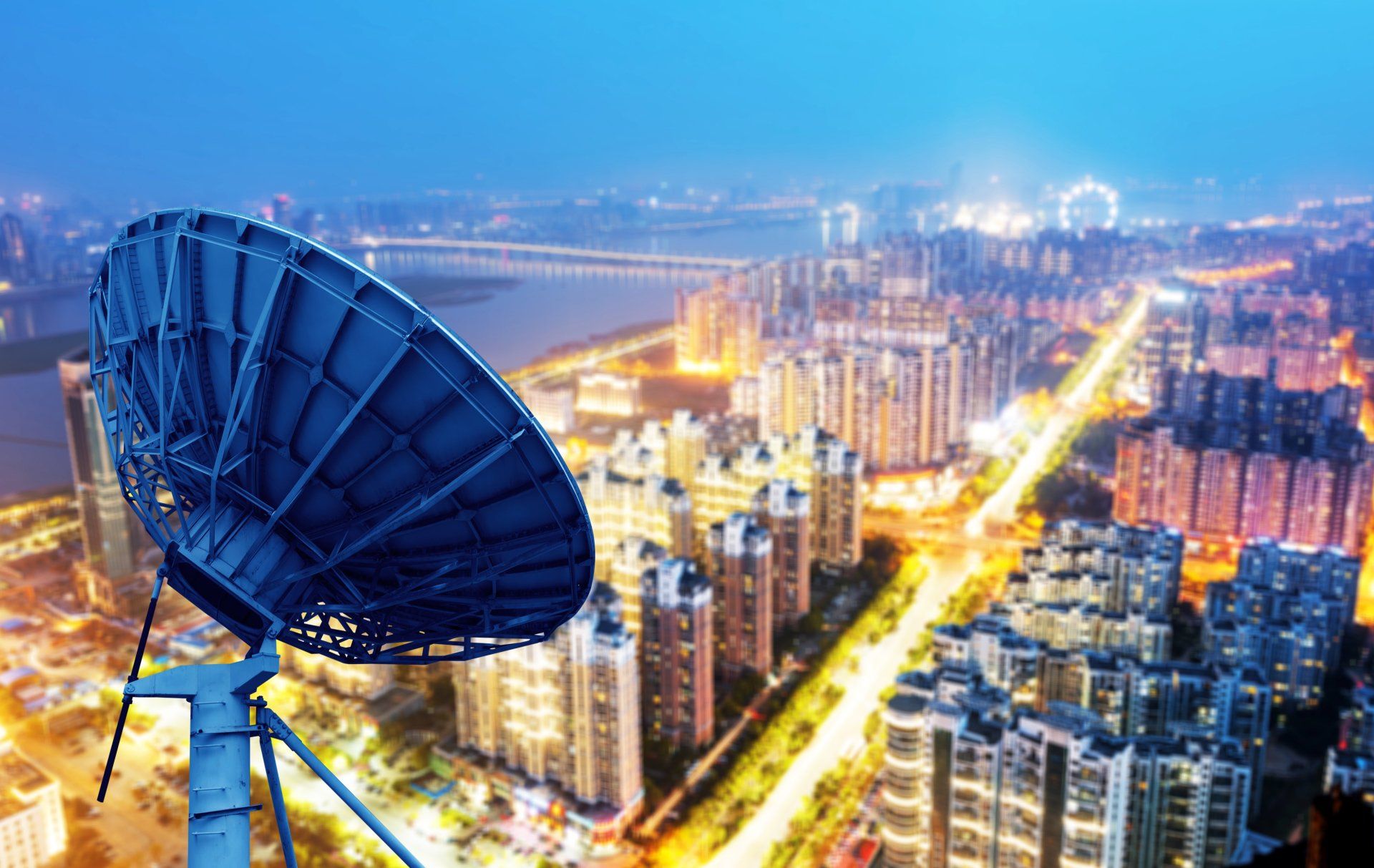 A satellite dish is sitting in the middle of a city at night.