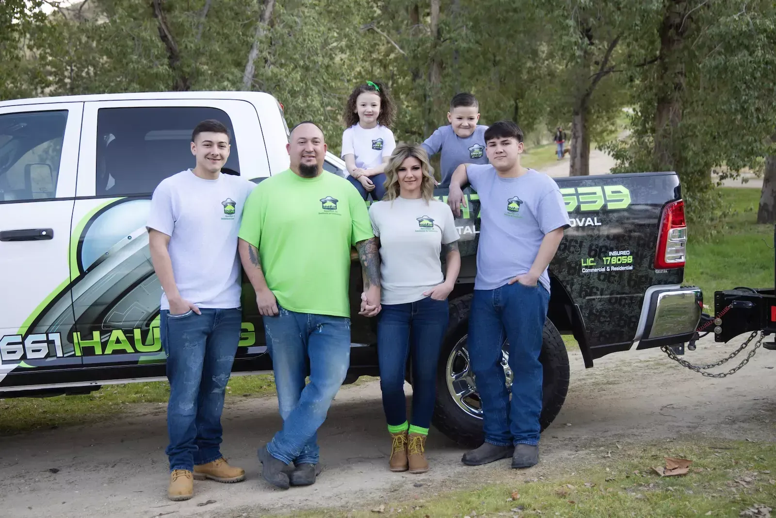 A junk removal family posing for a picture in front of a truck in Bakersfield