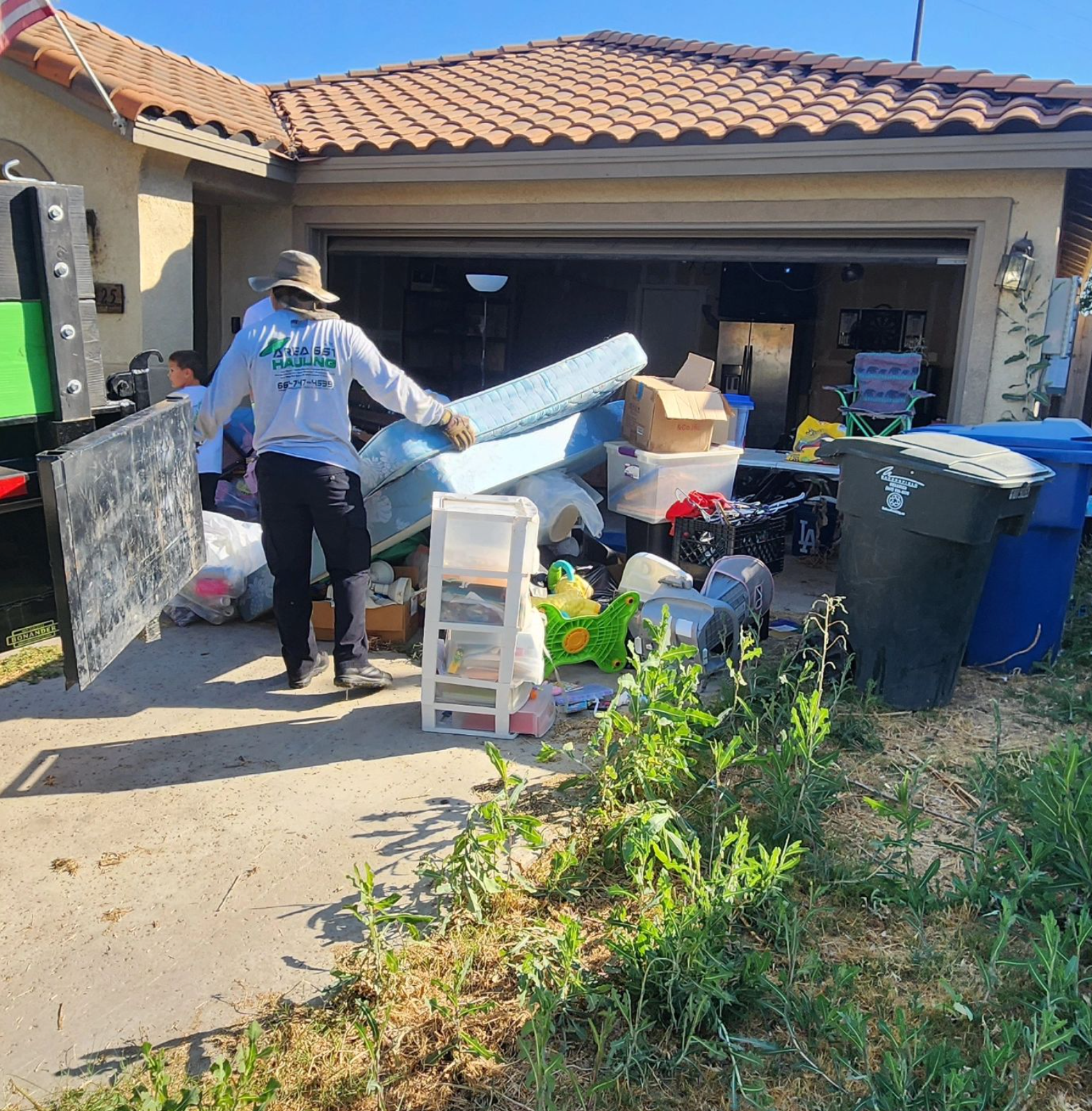 An estate cleanout in progress in Bakersfield. A man is standing in front of a garage full of garbage.