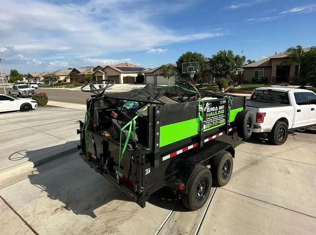 A dumpster trailer full of junk is being hauled by a truck in Bakersfield