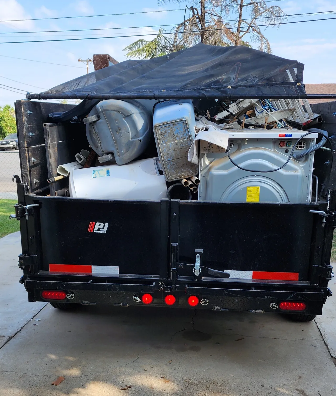 A dumpster with a washer and dryer in it being hauled off to the dump