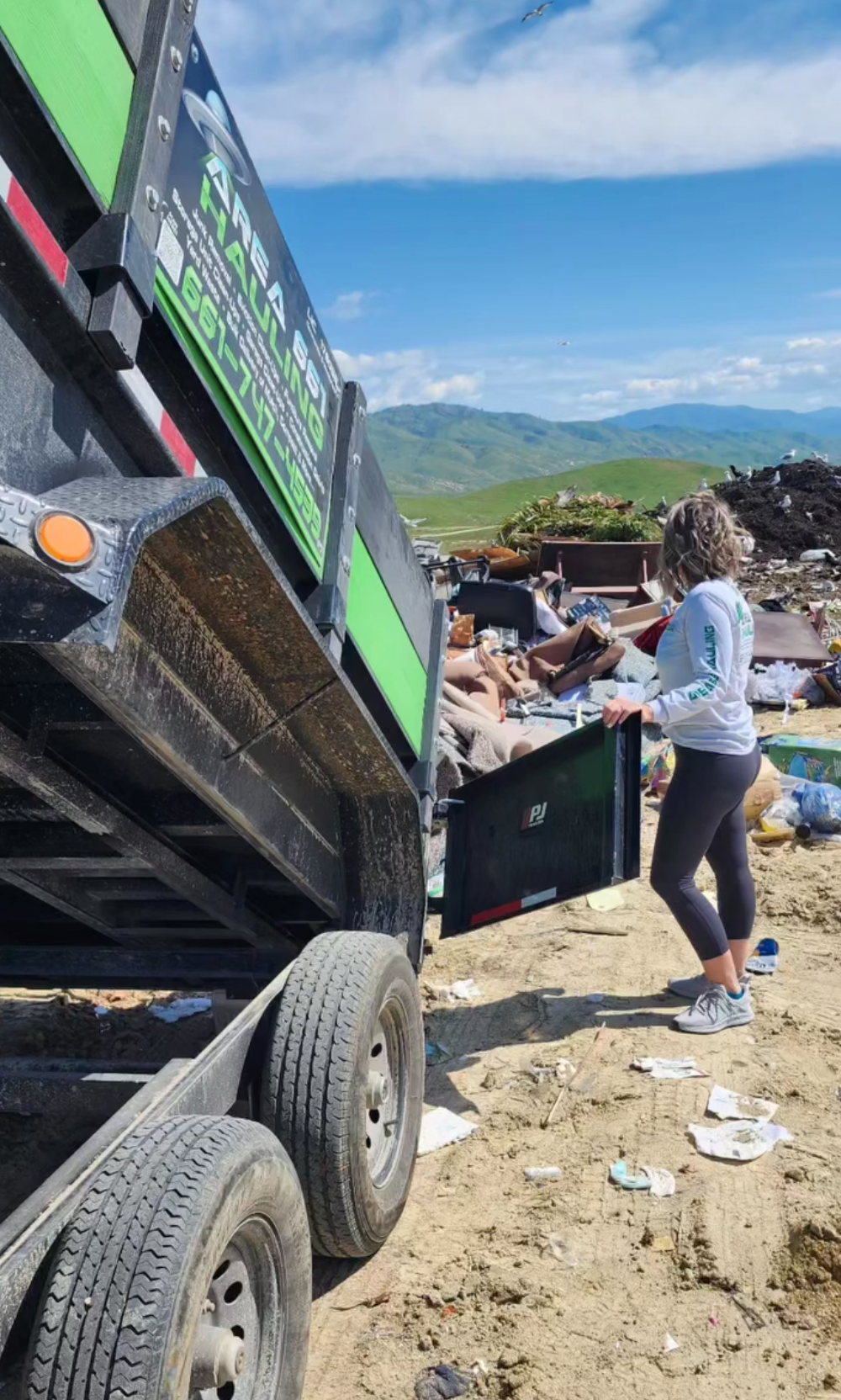 A man is standing in front of a garage full of junk.
