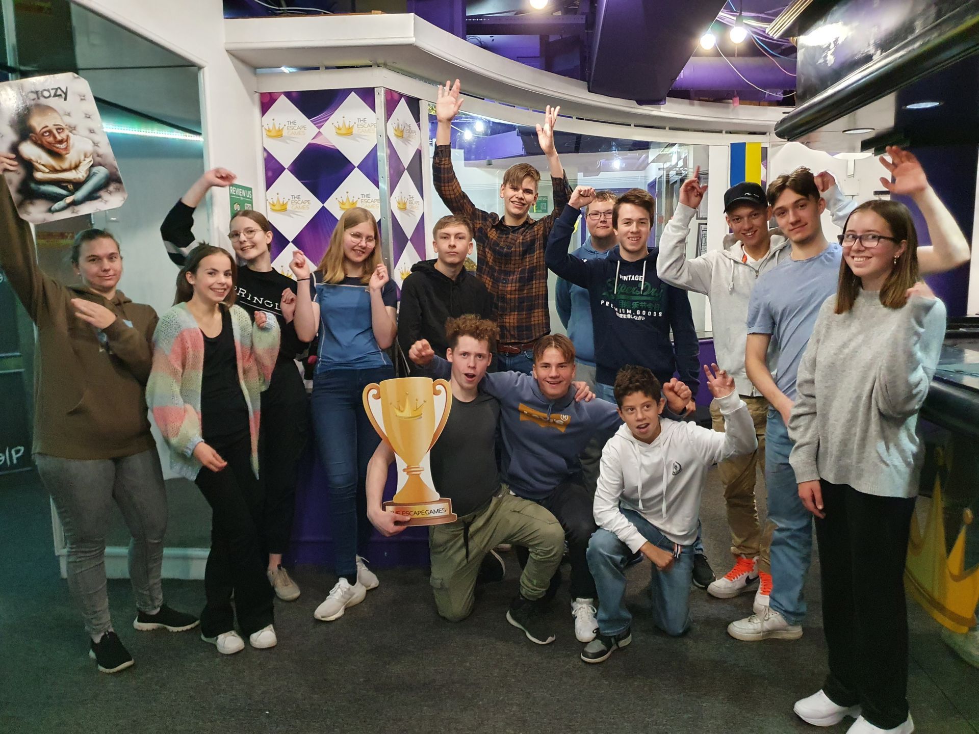 En gruppe tenåringer feirer og holder et trofé. Lilla og hvitt interiør med dekorasjoner.