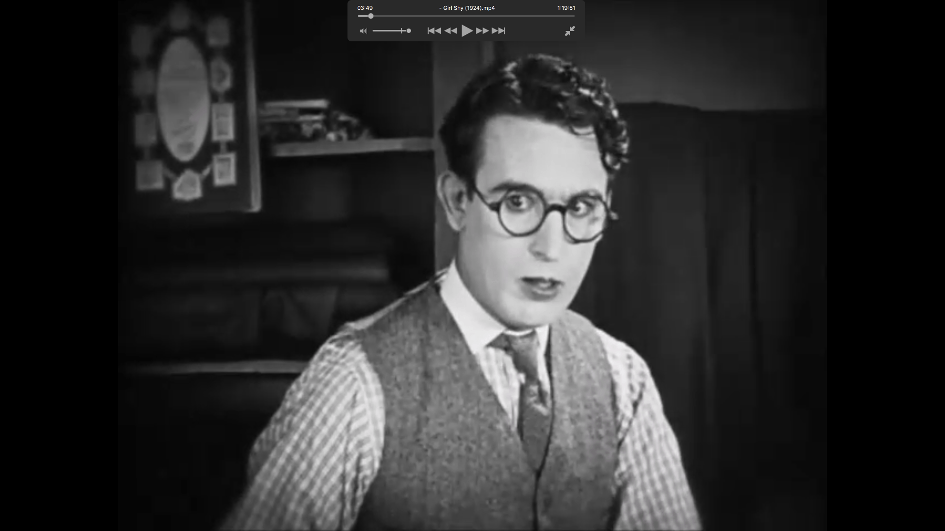 En mann med briller og vest stirrer på kameraet med et overrasket uttrykk, svart-hvitt-film.