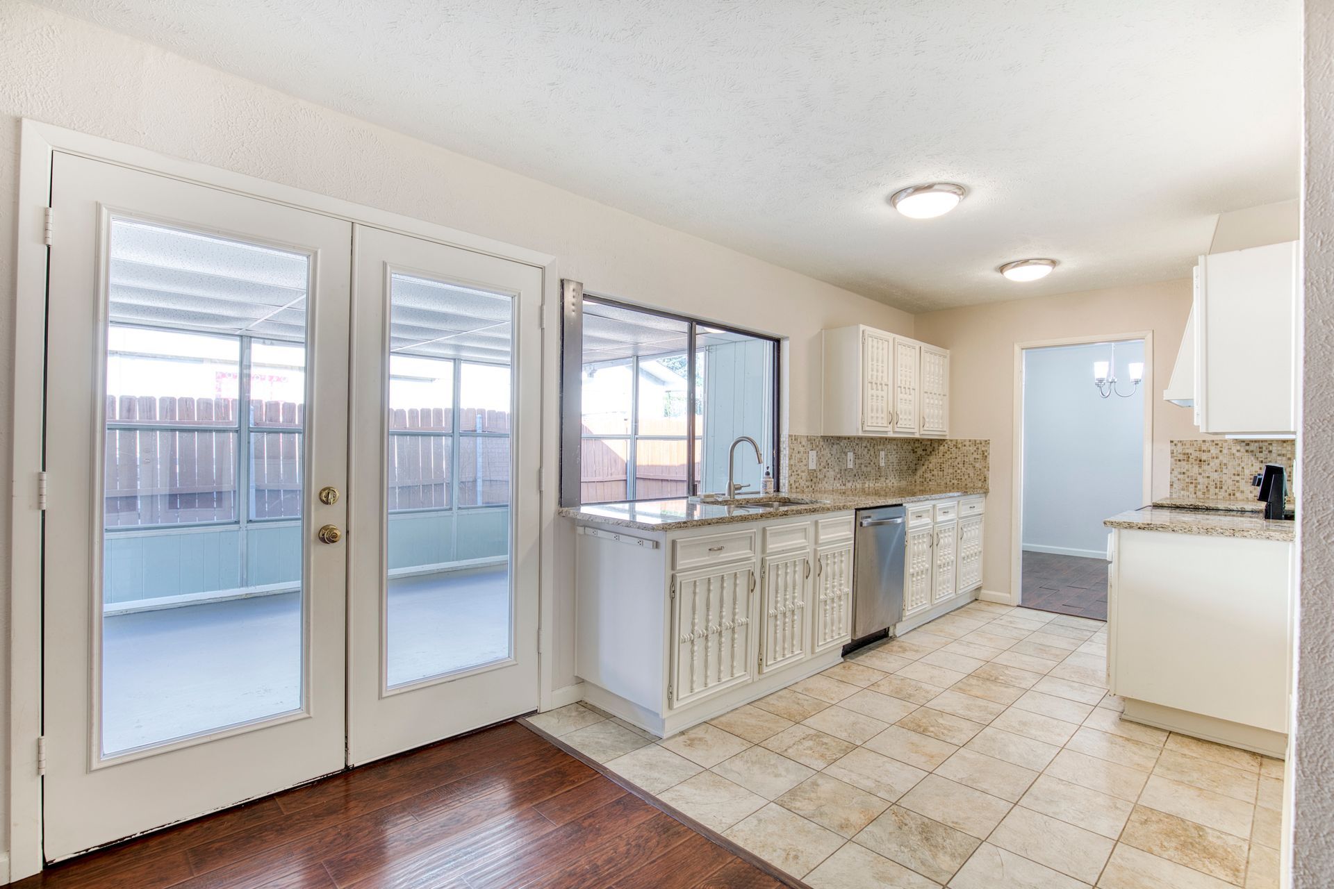 An empty kitchen with white cabinets and stainless steel appliances.