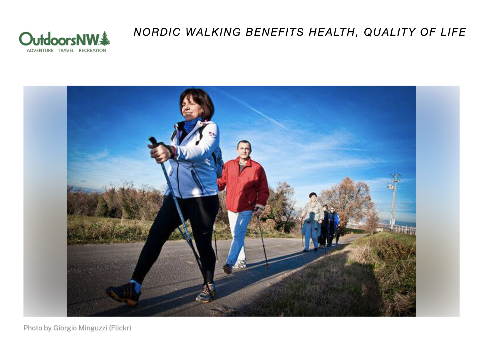 A group of people are walking down a road with nordic walking poles.