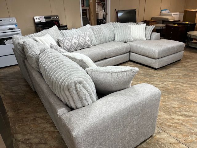 Gray sectional sofa with multiple pillows in a showroom.