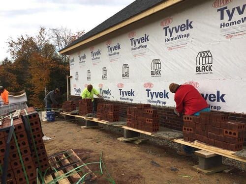 Workers installing blocks in wall — Construction Company in Bloomington, IN