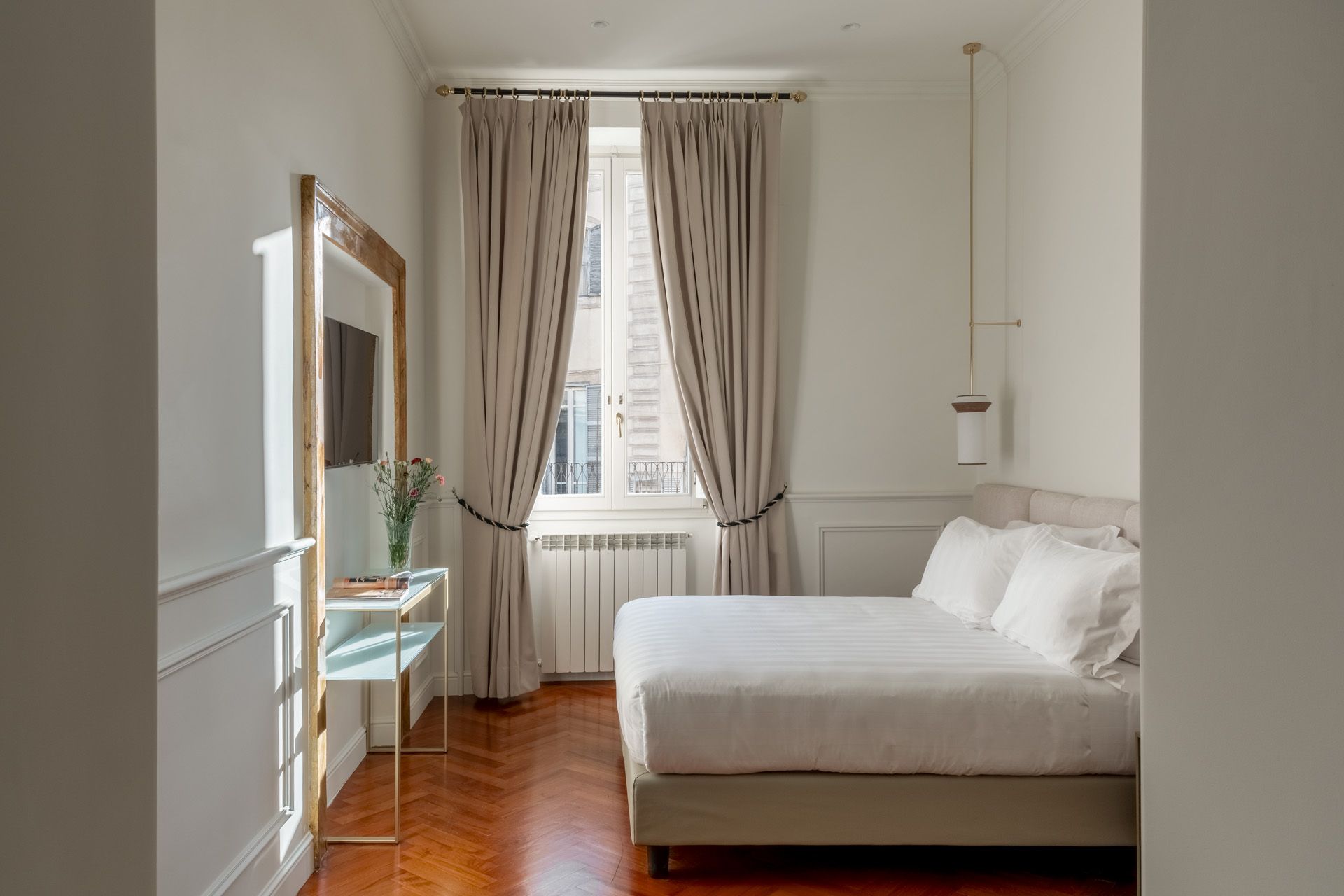 Bedroom with white walls, window with beige curtains, and a bed.