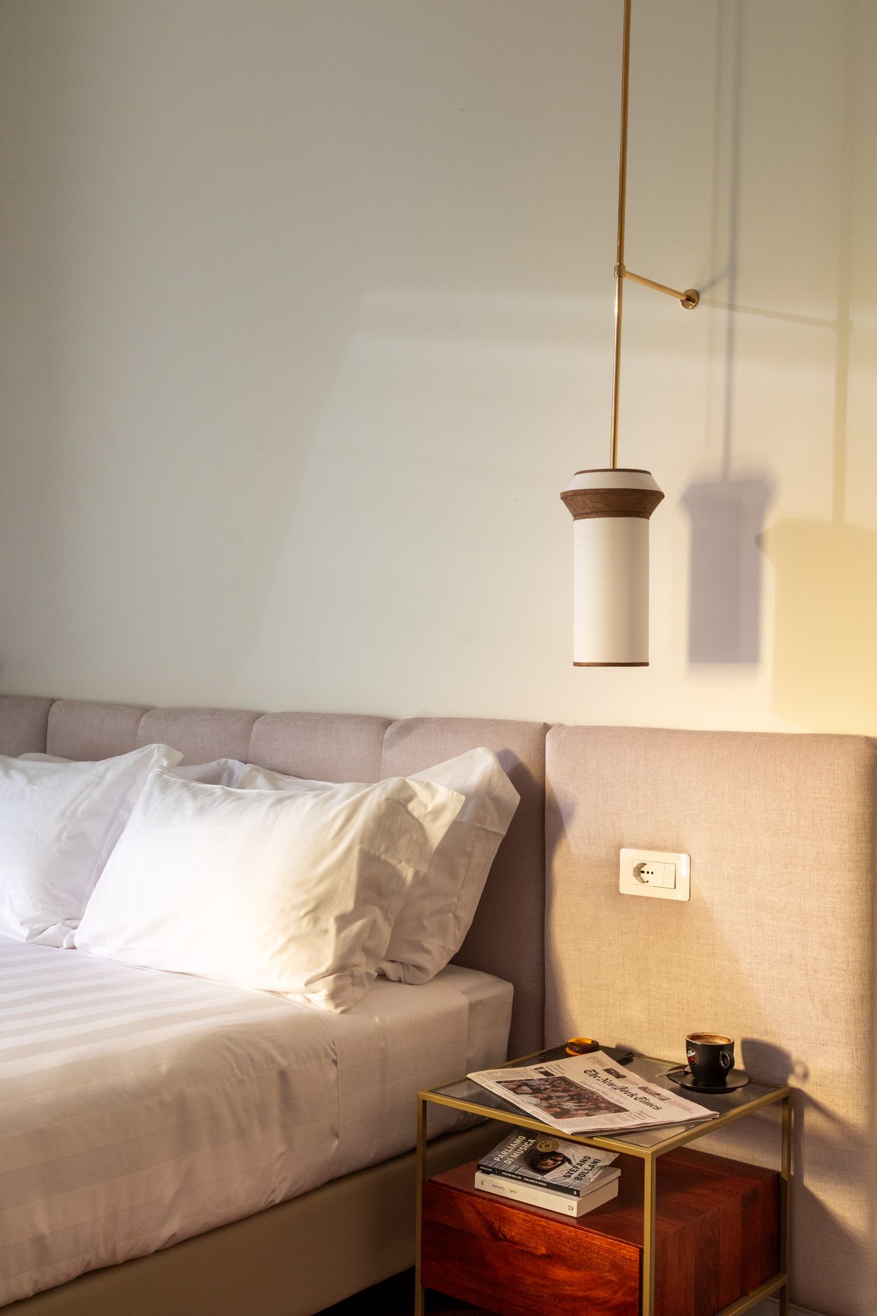Bedroom interior with bed, nightstand, and hanging pendant light.