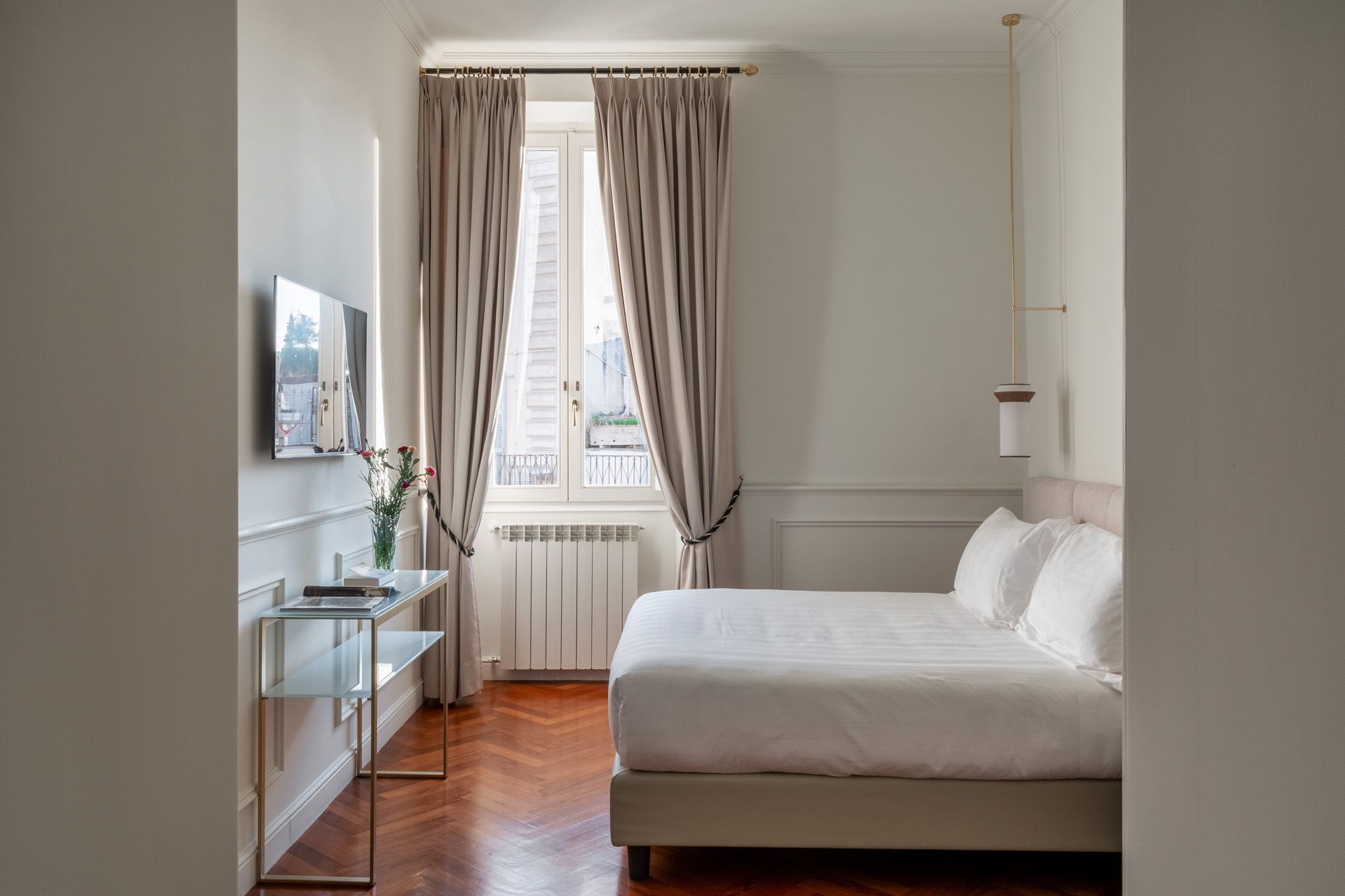 Bedroom with a bed, window, TV, and decorative curtains. Features a clean, bright aesthetic.