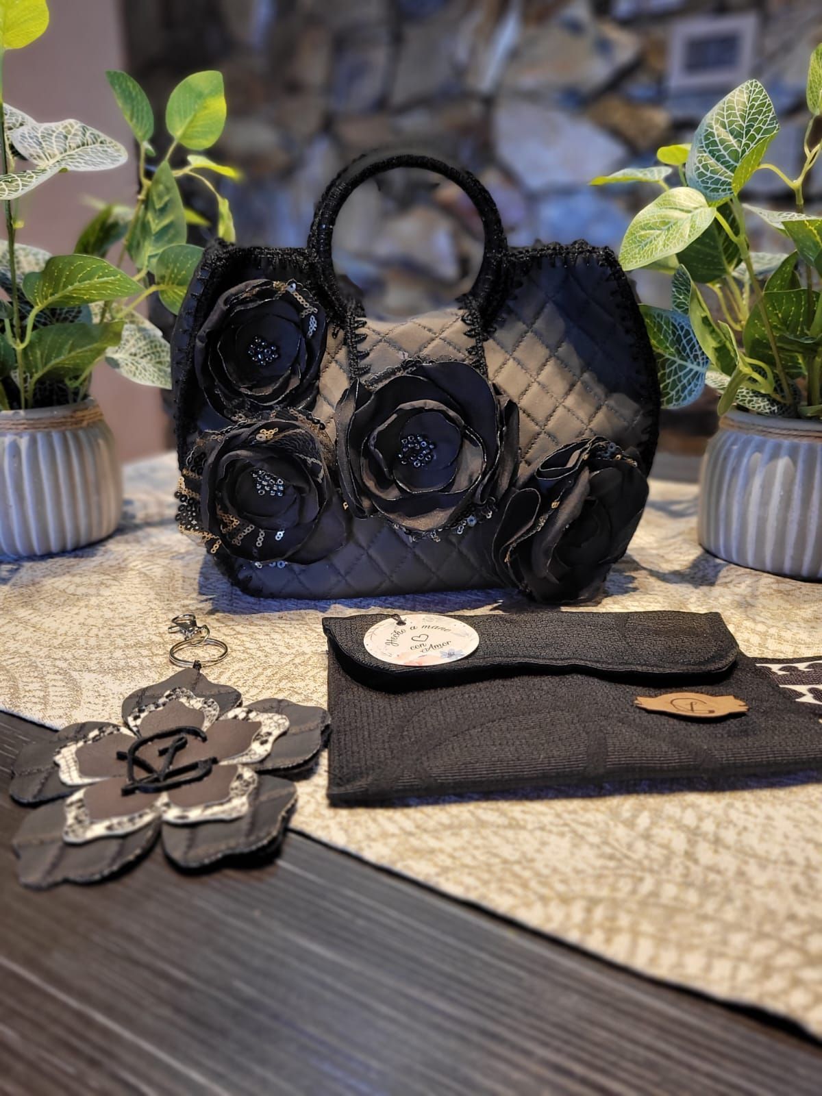 Un bolso negro con flores está sobre una mesa.