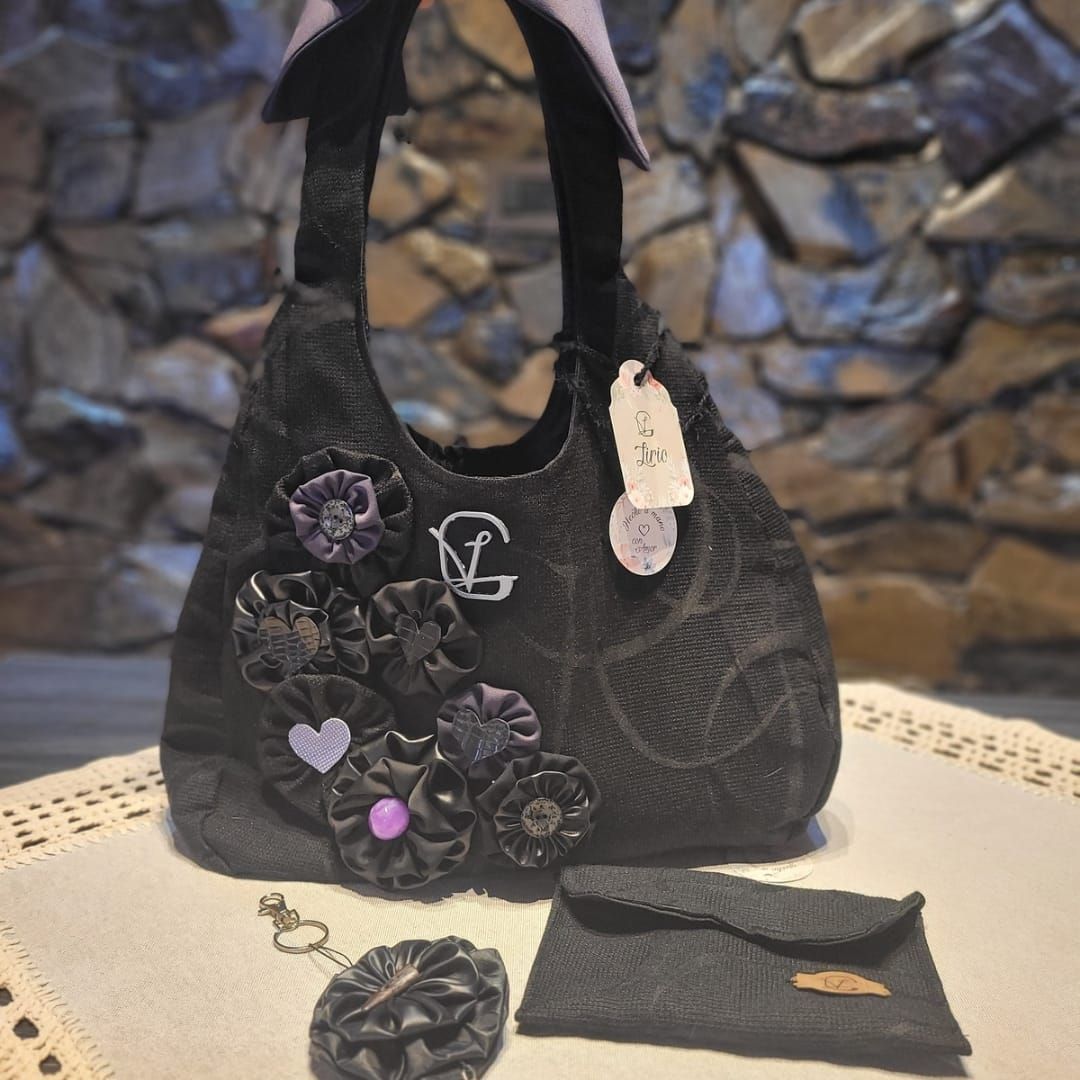 Un bolso negro con flores moradas reposa sobre una mesa.