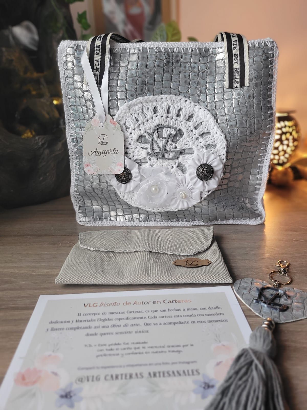 Un bolso de plata está sobre una mesa de madera al lado de un trozo de papel.