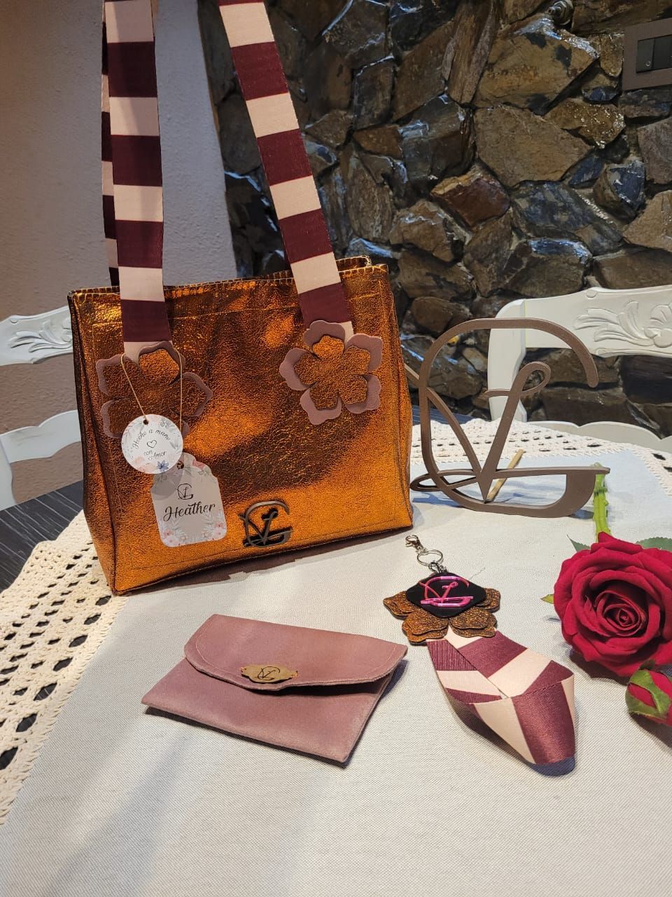 Un bolso y una billetera están sobre una mesa al lado de una rosa.