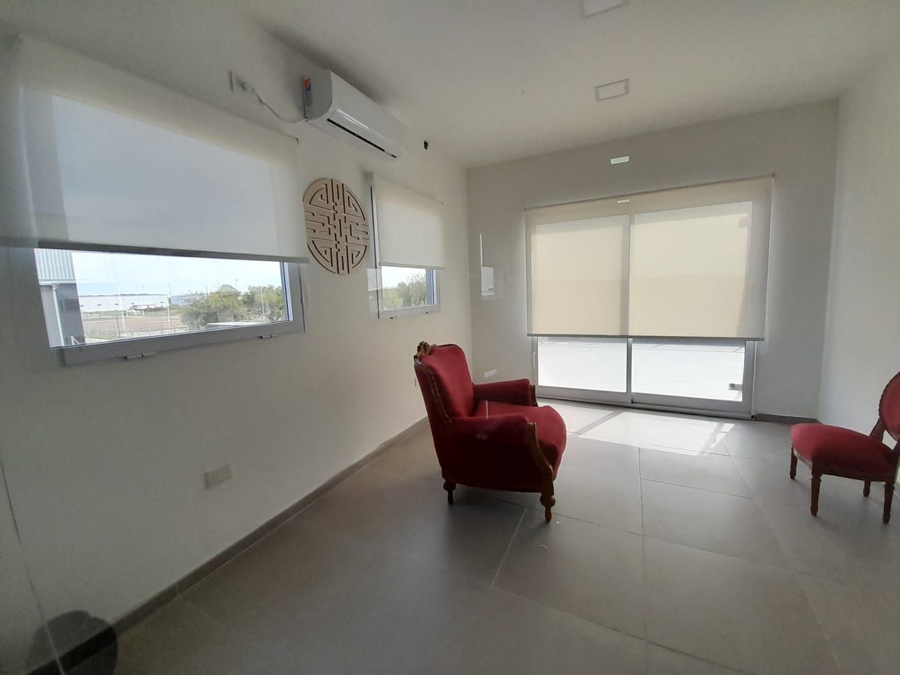 Una habitación luminosa y minimalista con suelo de baldosas, dos sillones rojos