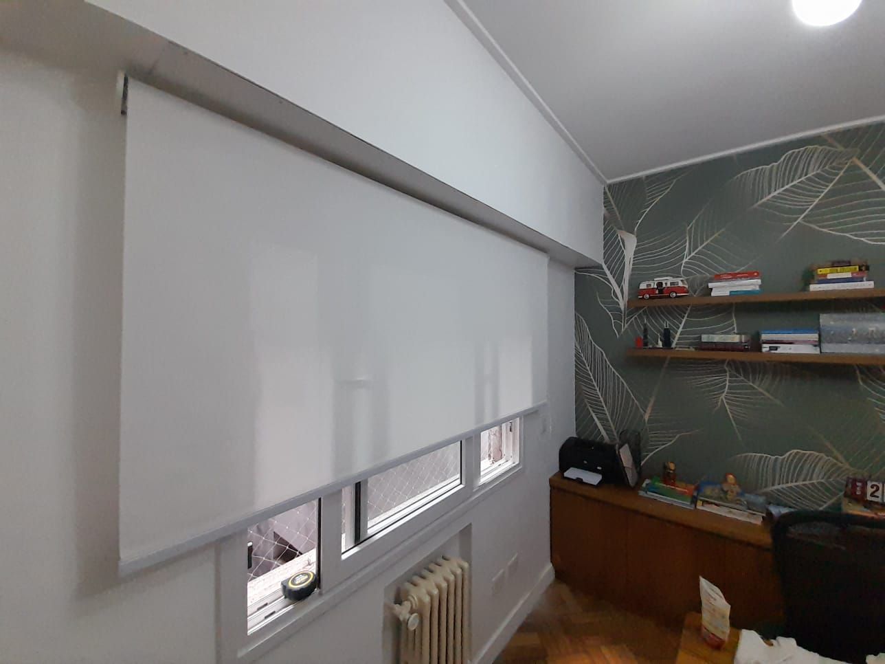 En una oficina en casa, una persiana enrollable blanca cubre