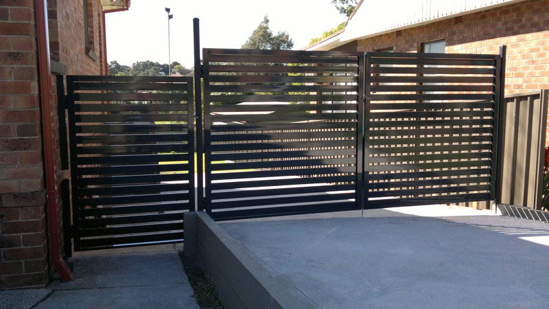 Black gate of a driveway in front of a house — Balustrading in Unanderra NSW